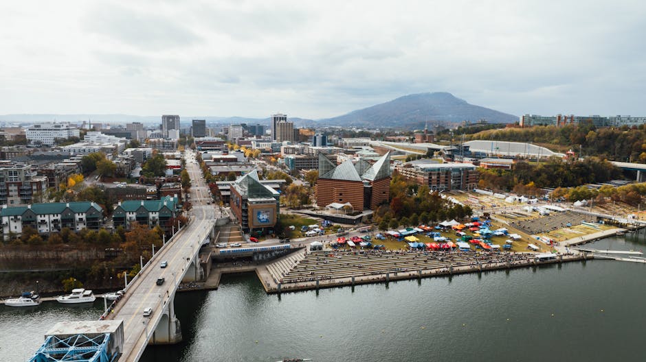 Aerial view of Chattanooga, TN, featuring bridges, riverfront, and cityscape under an overcast sky.