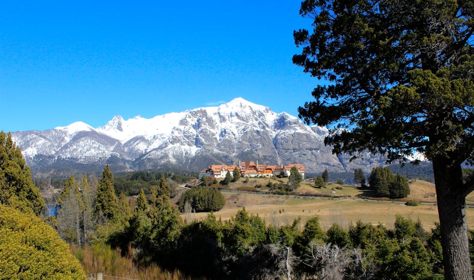 Beautiful landscape of Llao Llao Hotel with snow-capped Andes mountains under a clear sky.