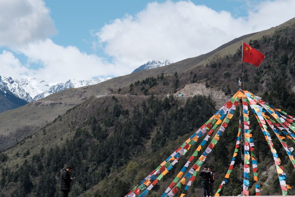 Vibrant prayer flags with a mountainous landscape, showcasing cultural and natural beauty.