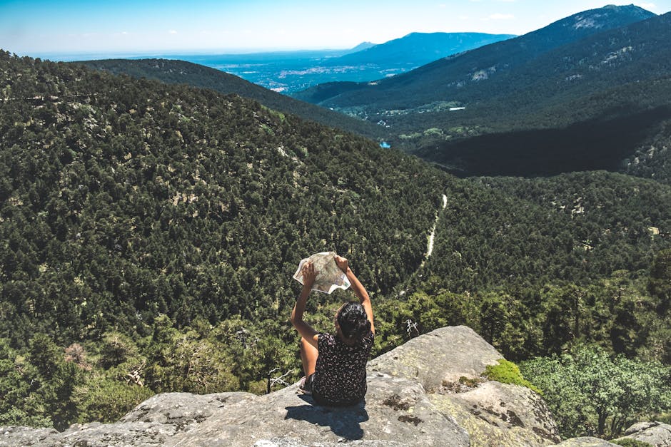 A woman explores a lush mountainous landscape, studying a map from a scenic viewpoint.