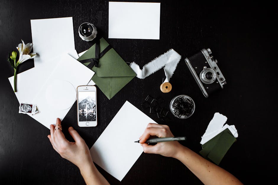 Top view of a creative workspace with stationery and a vintage camera on a dark background.