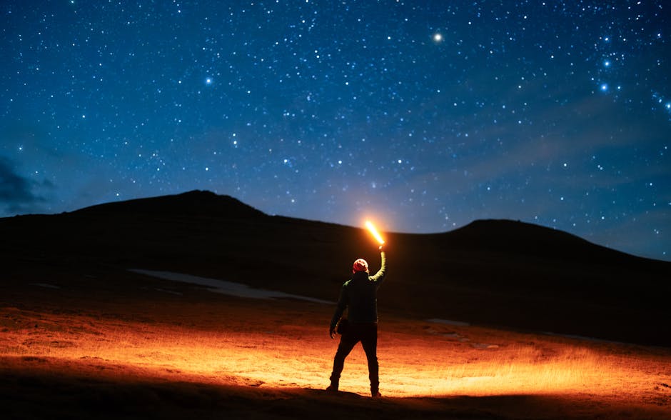A lone hiker holding a lantern illuminates the night sky filled with stars, creating a magical scene.