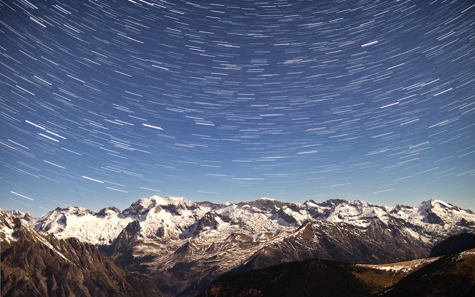 Captivating night sky with star trails swirling above snow-capped mountains. A breathtaking natural panorama.